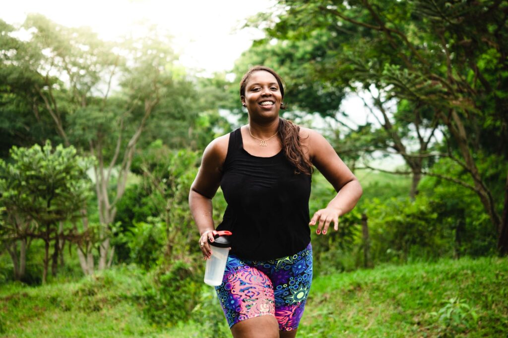 woman running through a green park to achieve her fitness goals